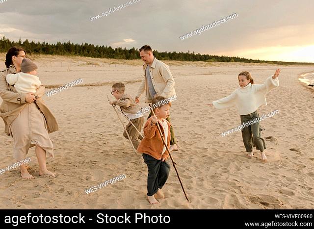 Happy father and mother having fun with children at beach
