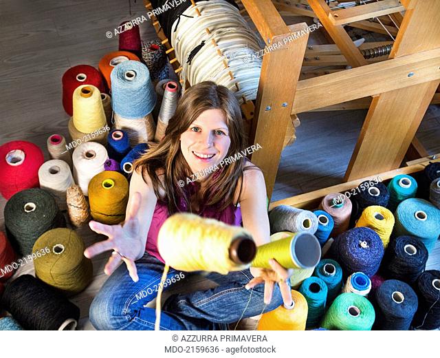 Girl sitting among coloured yarns. Foligno (Italy), 21/06/2014
