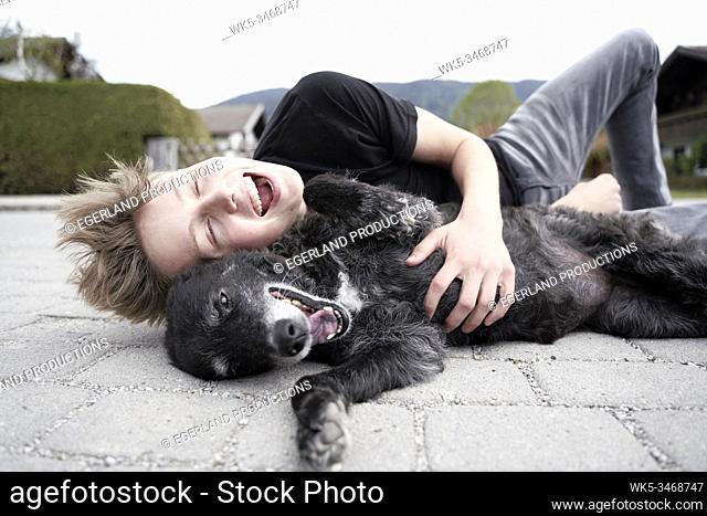 Teenager playing with his dog, in Gaissach, Bavaria, Germany