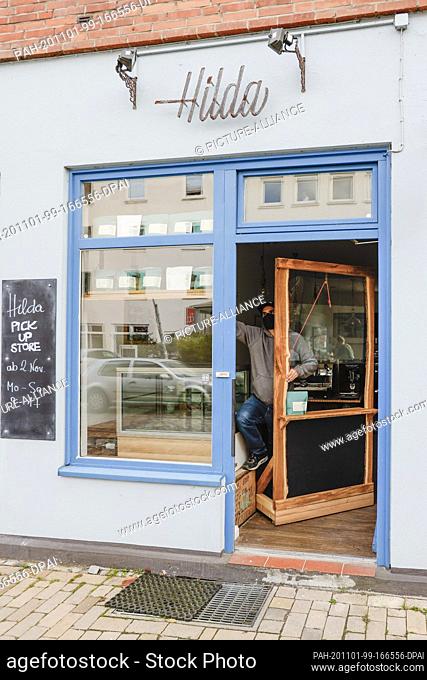 01 November 2020, Schleswig-Holstein, Kiel: Viktor Gottschalk installs a mobile goods issue at the entrance door of his café ""Hilda"" in the city centre of...