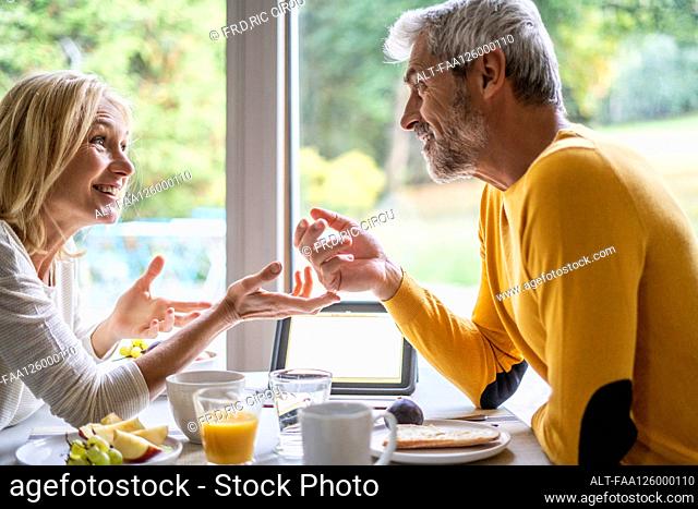 Smiling mature couple talking with each other while having breakfast