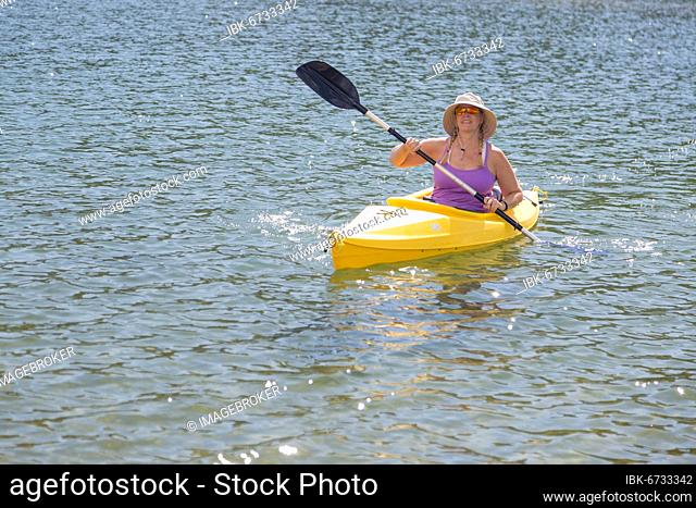 Woman kayaking on beautiful peaceful mountain lake