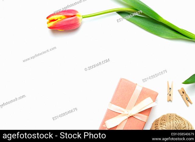 Gift box with red tulip flower on white background. Floral composition, flat lay, top view, copy space