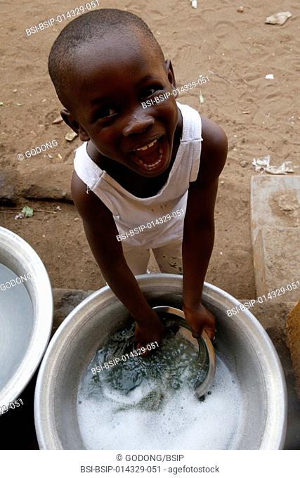 african primary school (togo). pupil having fun while doing the dishes after lunch