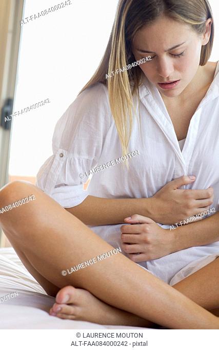 Young woman clutching stomach in pain