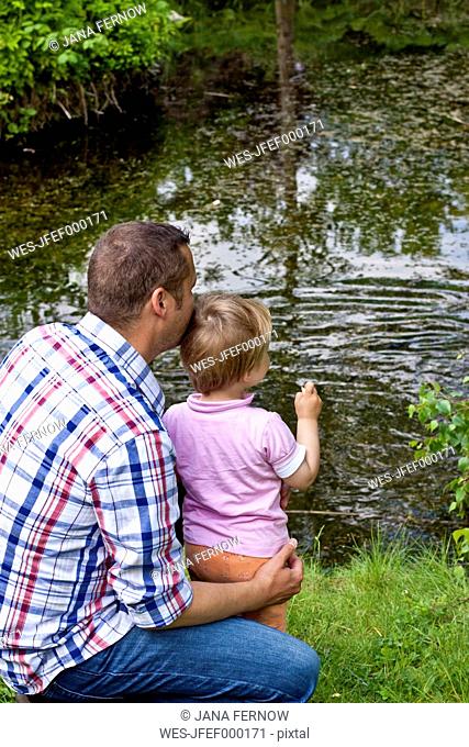 Germany, Kiel, girl stands on a pond with its father feeding ducks