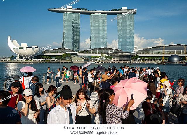 Singapore, Republic of Singapore, Asia - Tourists visit Merlion Park along the Singapore River with the Marina Bay Sands Hotel in the backdrop