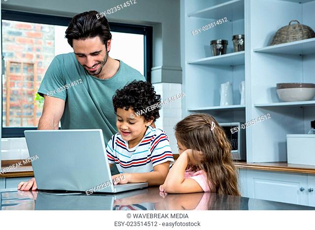 Smiling father and children using laptop