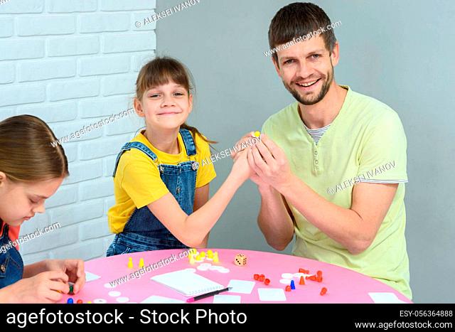 Girl and dad hold chips while playing a board game