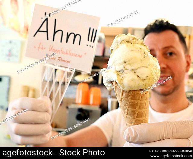 PRODUCTION - 29 July 2023, Baden-Württemberg, Gaggenau: Alessandro Cimino shows off an ""um"" ice cream at his Rimini ice cream parlor
