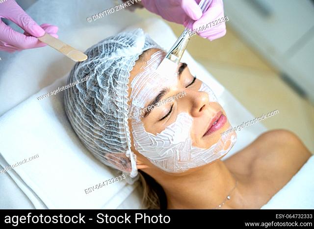 Unrecognizable cosmetologist doing cleansing beauty procedures in clinic, peeling and anti aging