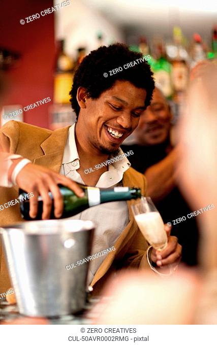 Bartender pouring champagne at bar