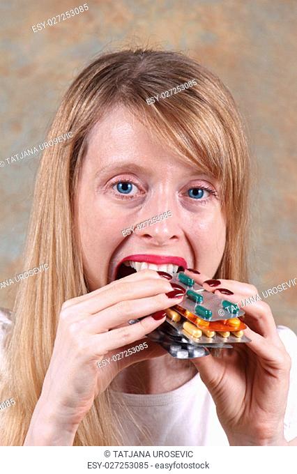 Young blonde woman eating prescription pills blisters