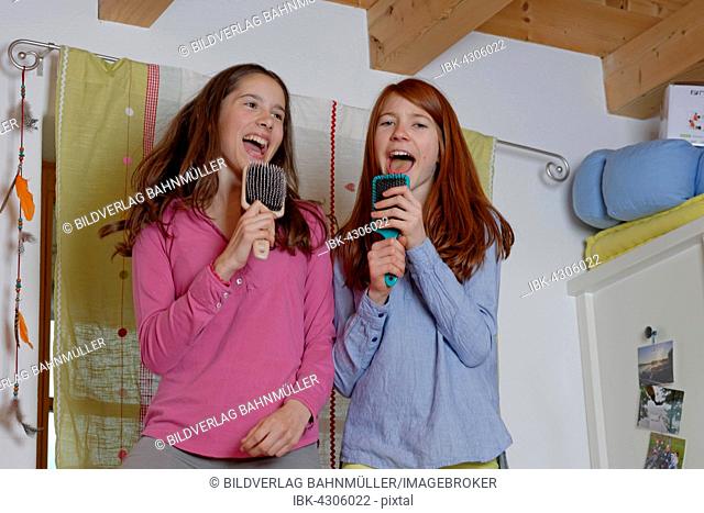 Girls, children singing into hairbrush as microphone, Germany