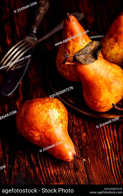 Few Golden Pears with Fork and Knife on Wooden Table. Vertical Orientation
