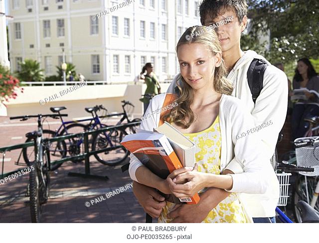 A young couple together standing by a bike rack