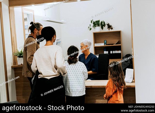 Family talking to receptionist in surgery