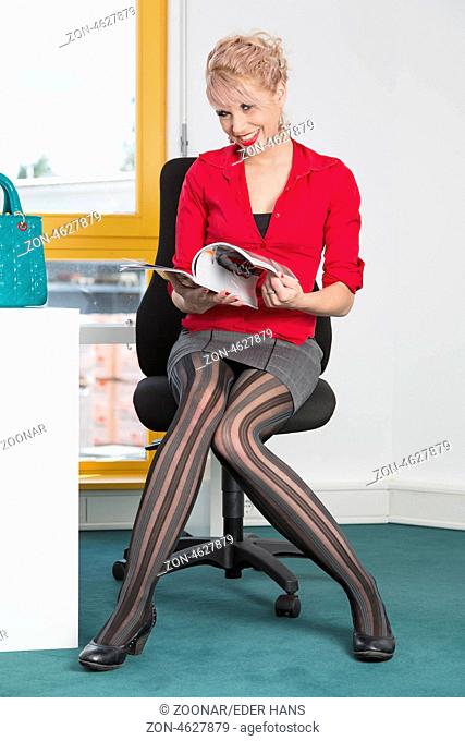 Sekretärin liest im Büro eine Zeitschrift