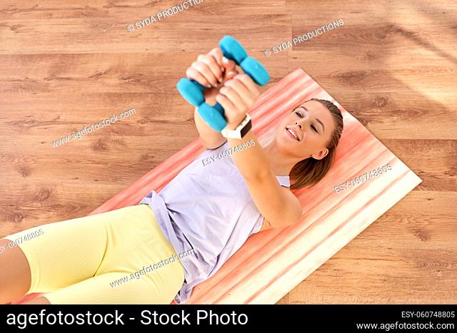 teenage girl with dumbbells exercising at home