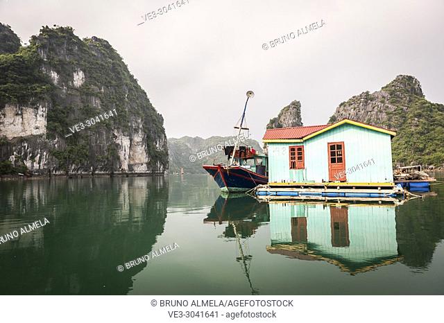 Fishing boat and traditional house in karst landscape of Ha Long Bay, Quang Ninh Province, Vietnam. Ha Long Bay is a UNESCO World Heritage Site