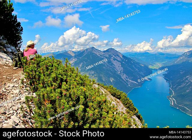 middle-aged woman enjoys the view from bärenkopf (1991m), achensee, on the left seebergspitze and seekarspitze, on the right rofan mountains, tyrol, austria