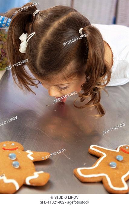A little girl licking honey from a work surface