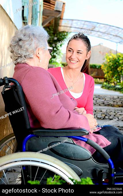 Cheerful young woman in a retirement house garden with a elderly senior woman