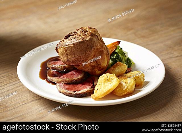 A traditional English roast beef dinner with gravy being poured