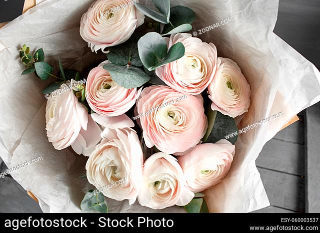 Bouquet of light pink ranunculus in vase on wooden background