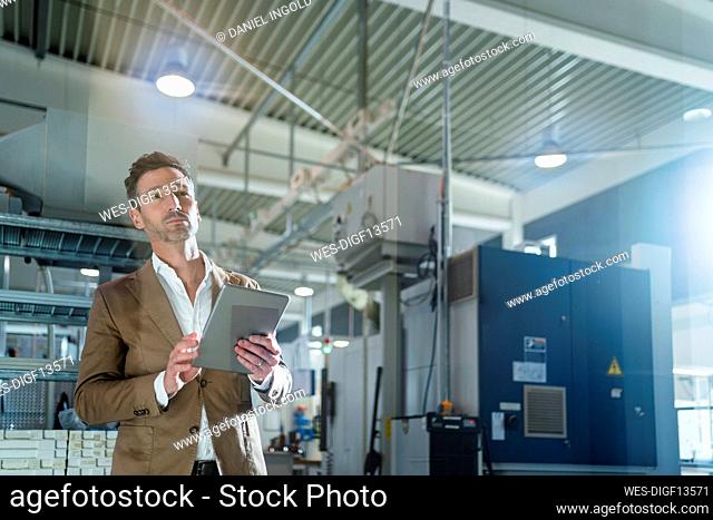 Male professional with digital tablet looking away in industry