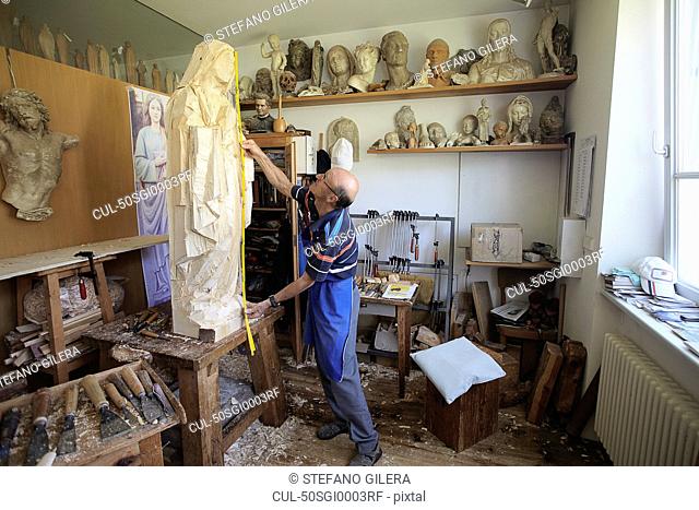Sculptor measuring wooden figure