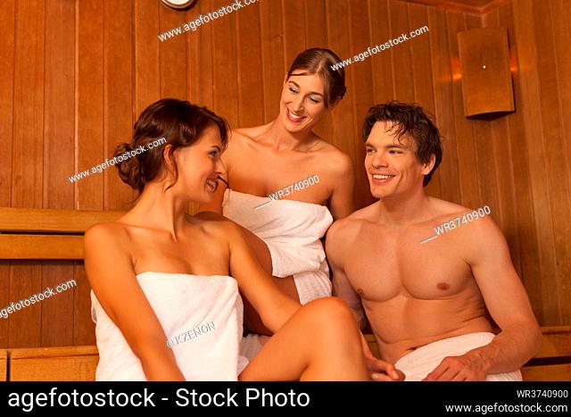 Three people (one male, two female) enjoying a hot sauna, having a casual chat