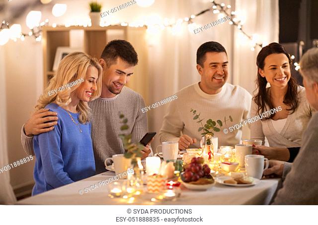 happy family with smartphone at tea party at home