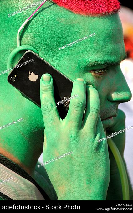 Portrait of young man, face painted in green color, hair painted in red color, talking by mobile phone, Lake Parade - LGBT Parade, Pride Parade