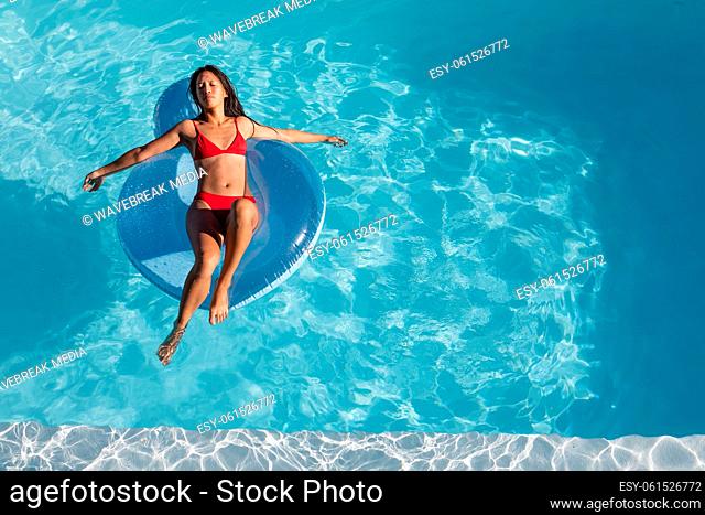 Mixed race woman sunbathing on inflatable in swimming pool