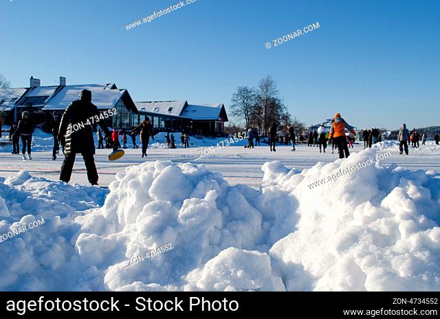 pile of snow closeup and active recreating leisure people in winter skating rink
