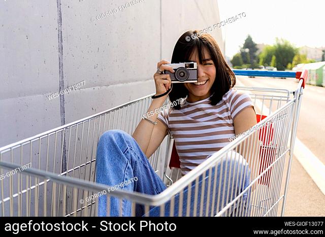 Young woman photographing through camera in cart