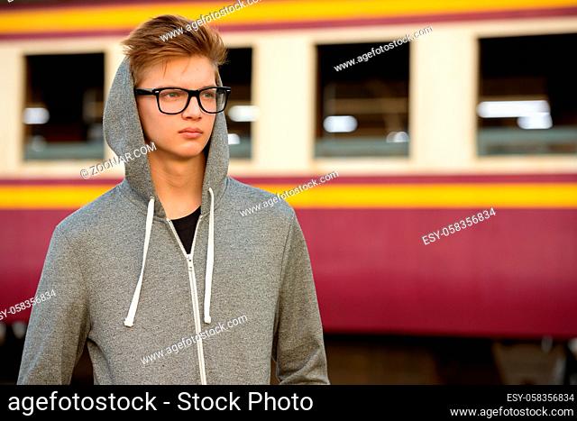 Portrait of young handsome teenage boy at the railway train station