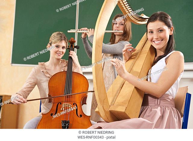 Germany, Emmering, Teenage girl and young women playing musical instruments