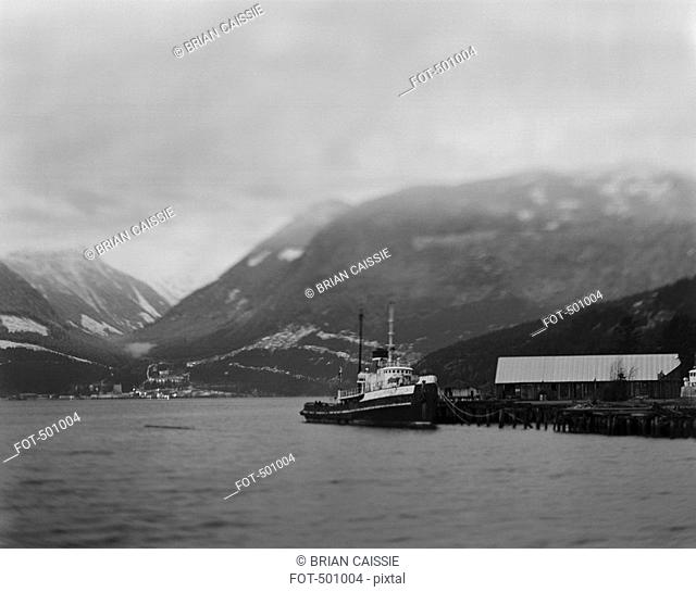 A tugboat in a harbor surrounded by mountains