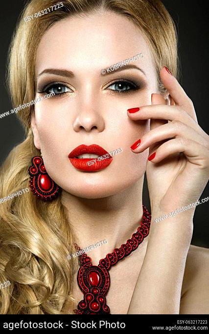 Beautiful blonde woman with evening make-up and red lips. Picture taken in the studio on a black background