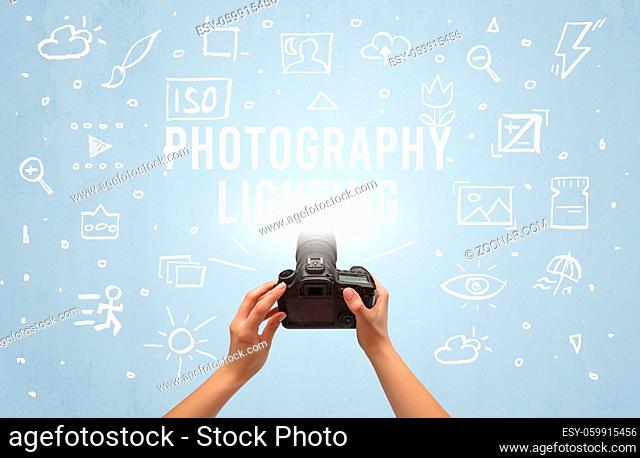 Hand taking picture with digital camera and PHOTOGRAPHY LIGHTING inscription, camera settings concept