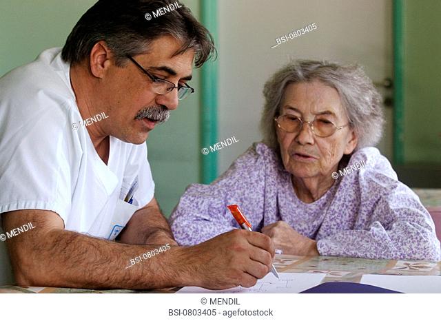 HOME FOR THE ALZHEIMER'S DISEASE<BR>Photo essay from hospital.<BR>Gerontology unit. The nurse's aide asks an Alzheimer's patient to recall her family genealogy