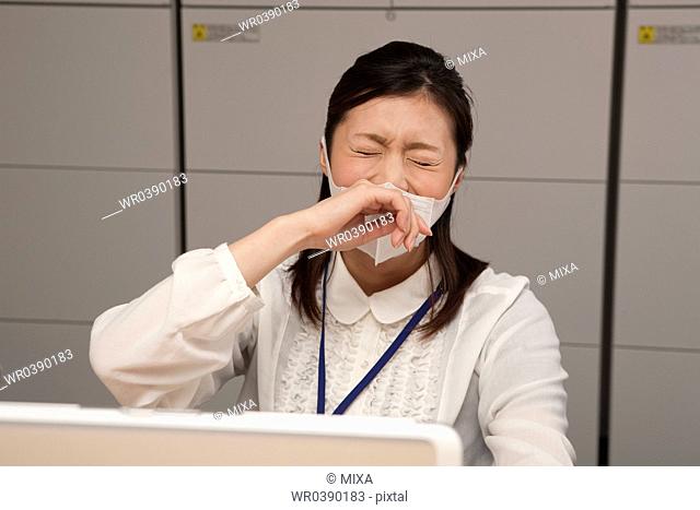 Young businesswoman wearing mask and sneezing