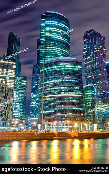 Business district of the city in colorful night lights. Midnight lights of a big city are reflected in the river