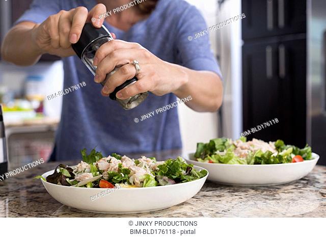 Mixed race woman seasoning salad