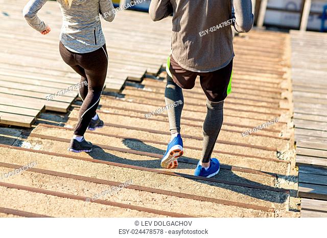 fitness, sport, exercising and lifestyle concept - close up of couple running downstairs on stadium