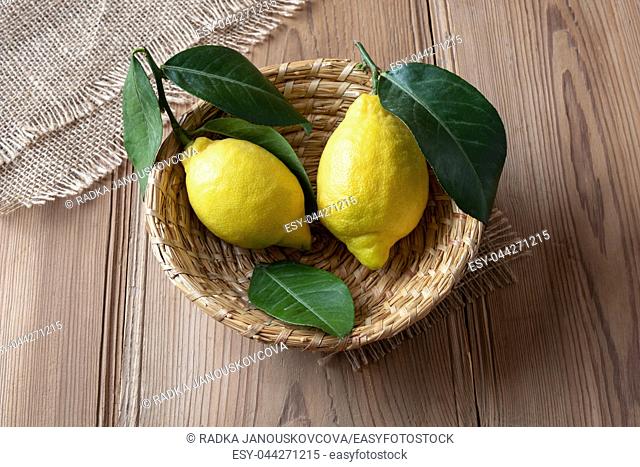 Two fresh lemons with leaves in a basket