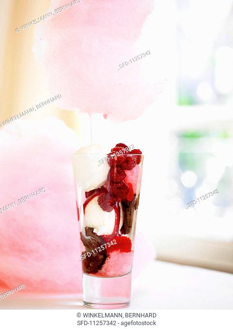 An ice cream dessert with fresh strawberries and pink candyfloss