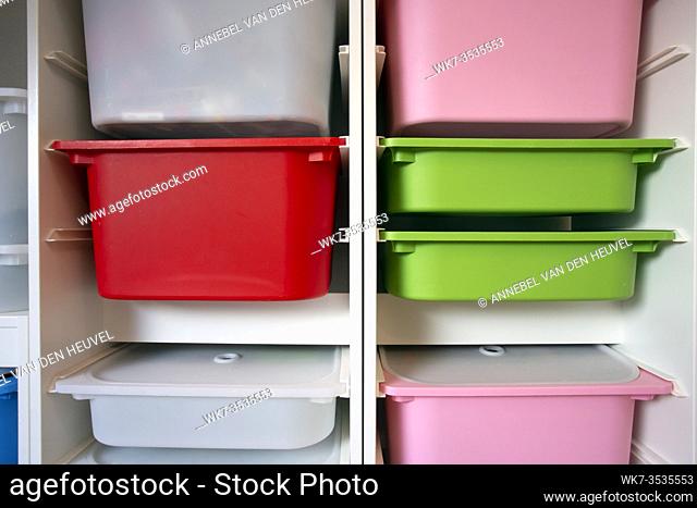Stack of plastic storage boxes in different colors, sorting system arrangement close-up
